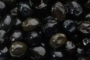 Delicate glimmer of shiny black olives nestled together in a bowl, showcasing a harvest's bounty...