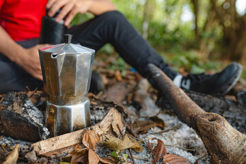 Coffee brewing in moka pot over campfire in forest setting