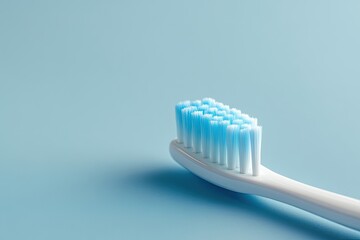 Close-up of a toothbrush head.  Light blue bristles on a white handle against a light blue background