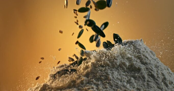 Super Slow Motion of A Colorful Mixed Seeds and Flour in Mid-Air - Sunflower, Pumpkin, Flax, and Sesame Seeds Blended  of Texture and Flavor Against a Golden Background at 1000 fps.
