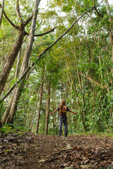 Traveler with open arms embracing nature in tropical forest trail in Costa Rica