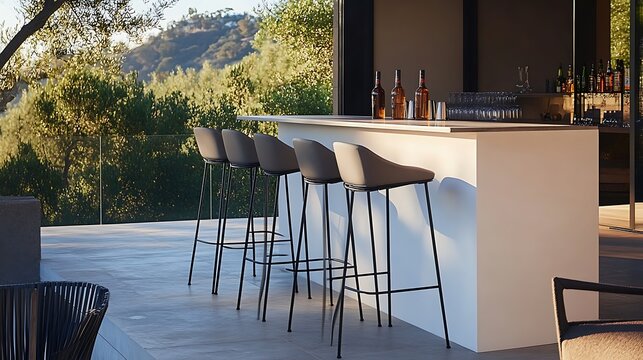 Modern outdoor bar setup with four high counter stools overlooking a green landscape for.