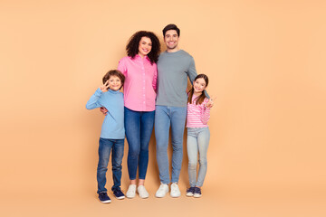 Happy family of four posing together on beige background showcasing love, bonding, and togetherness...
