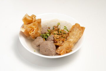 A white bowl of Bakwan Malang, featuring meatballs, noodles, fried wontons, and tofu in a clear broth. A savory and flavorful Indonesian soup.