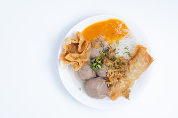 A white bowl of Bakwan Malang, featuring meatballs, noodles, fried wontons, and tofu in a clear broth. A savory and flavorful Indonesian soup.