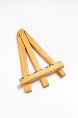 A small, light wooden easel, possibly for tabletop display or miniature art. Shows signs of use with paint marks. Isolated on white.