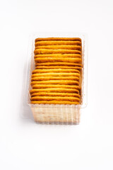 A stack of biscuits in a clear plastic container, isolated on a white background. A common snack found in North Jakarta and throughout Indonesia.