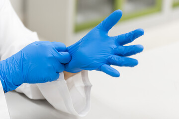 Woman doctor putting blue latex medical gloves on white background.Surgeon wearing gloves before...