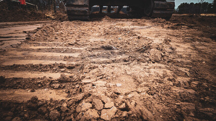 dirt mixed with tracks from an excavator that is slightly visible in the background. construction close-up design element