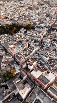 Aerial drone view of Nardo, a historic town in southern Italy, bathed in golden sunset light. The old towns dense architecture, whitewashed buildings, and narrow streets highlight its rich cultural
