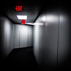 dimly lit hallway with exit sign. passenger boarding bridge or jetway. enclosed, elevated passageway extending from airport terminal gate to airplane. isolated color.