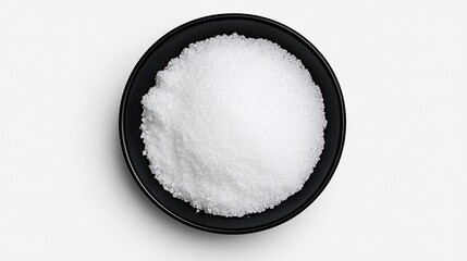 Top view of white crystalline powder in a black bowl on a white background