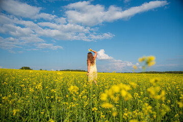 A girl walks through a blooming field on a warm summer day