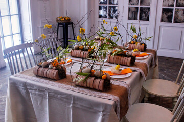 Easter table setting in yellow colors with floral arrangements of yellow flowers, eggs and lilies of the valley