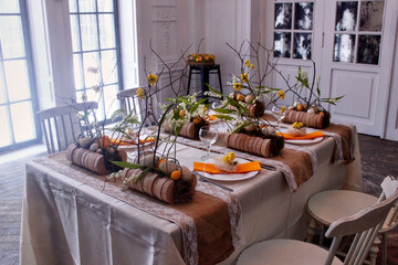 Easter table setting in yellow colors with floral arrangements of yellow flowers, eggs and lilies of the valley