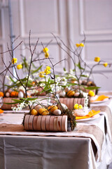 Easter table setting in yellow colors with floral arrangements of yellow flowers, eggs and lilies of the valley