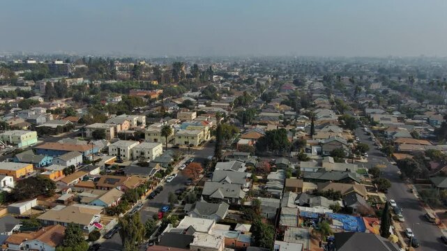 Aerial view of the South Los Angeles. Houses, buildings, cars, trees along the streets. Typical urban residential area of Los Angeles. Drone shot flying up. Real estate concept
