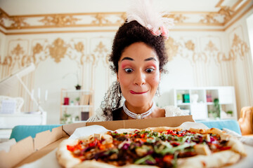 Young woman in elegant styling excitedly enjoys modern pizza in a retro classic interior