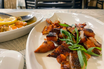 crispy fried pork belly served on a plate and sprinkled with green onions