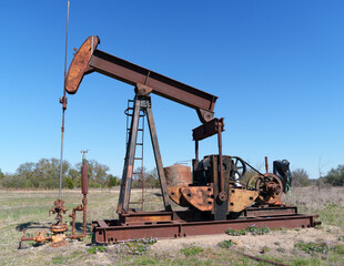 Idle, rusty oil well pump jack abandoned in field in West Texas.