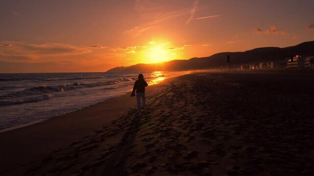 Atardecer dorado con silueta de chica caminando por la playa