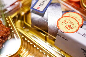 お寿司のパックに貼られたスーパーマーケットの割引「半額」シール