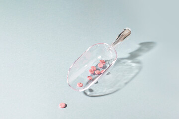 Pink tablets in a transparent spoon,