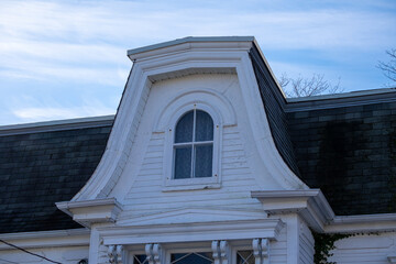 The exterior of a vintage, historical Second Empire Style mansard roof with black shingles, closed...