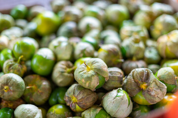 A bulk bin of fresh-pied cape gooseberries or husk cherries for sale at a farmers' market. The small, round, yellow, edible Peruvian fruit, ground cherries, have a dried papery husk on the outside.
