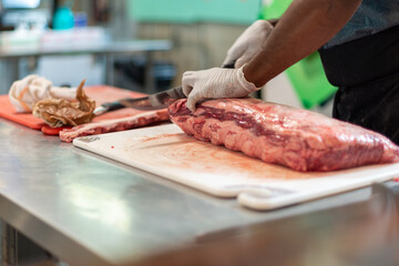A closeup of a large fresh prime rib beef roast sitting on a white plastic cutting board in a...