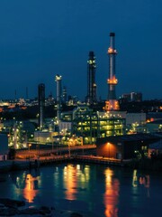 Industrial complex illuminated at night near the waterfront featuring smokestacks and machinery
