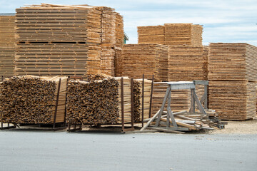 A bulk supply of lumber stacked on pallets in a lumberyard. A large amount of material has been sawed at a manufacturing yard.The boards are of various lengths and thickness.The new timber is for sale