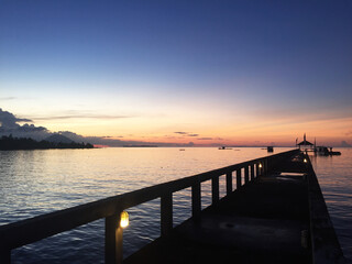 Obraz premium Stunning views from the pier out to sea to the horizon at dusk with the shadows of the mountains in the distance.