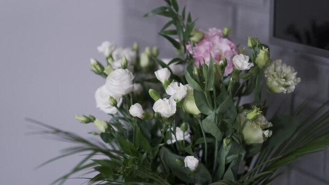 Fresh bouquet of white and light pink lisianthus with green foliage in a modern indoor setting

