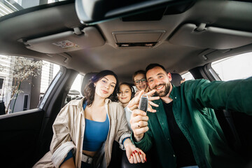 A happy young family in a modern car dealership after completing the purchase of a new family car....