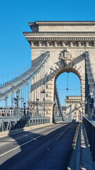 Budapest, Hungary - January 20, 2024: Close-up of Szechenyi Chain Bridge with historic stone arch and intricate metal structure on a cloudy day
