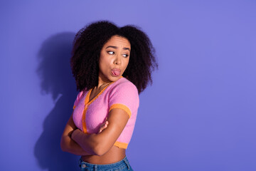 Young stylish woman expressing playful attitude with a tongue-out gesture, standing casually...