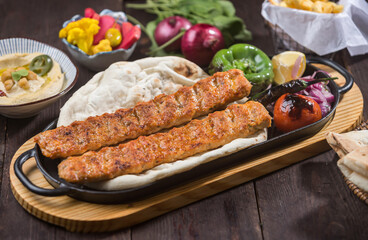 Chicken Kebab Platter served on tray grilled chicken kebabs, flat bread, hummus, and various sides side view of Middle Eastern dish