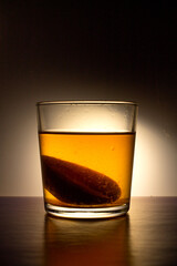 Transparent glass with compote and half a peach on a black background