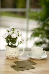 A cup of coffee, flowers and an envelope. Office desk with a cup of coffee