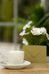 A cup of coffee, flowers and an envelope. Office desk with a cup of coffee