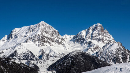 Fototapeta premium Breathtaking view of snowy mountain peaks under a clear blue sky; an ideal winter landscape showcasing the beauty of nature and tranquil alpine scenery. 
