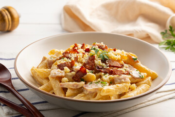 Creamy Penne Pasta Carbonara sauce bacon topped with parmesan cheese and crispy bacon in white plate.