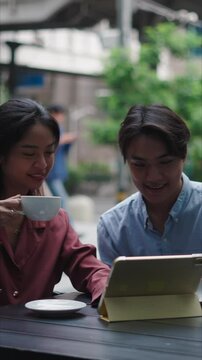 Asian b&uacute;shines copule analyzing information on tablet at outdoor cafe