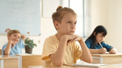 Smart elementary student looking at teacher while attend in classroom. Diverse smart student sitting at classroom while listening teacher explain about classwork or test. Education concept. Pedagogy.