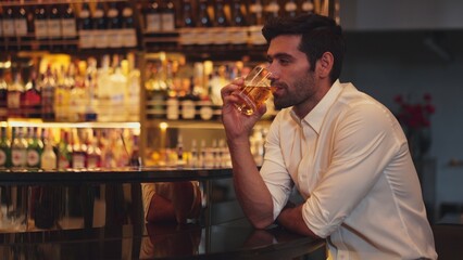 Smart man in white shirt drinking cocktail Old fashioned of special party beverage vibrant waiting for friends or couple at nightclub on Friday meeting night time at luxurious counter bar. Vinosity.