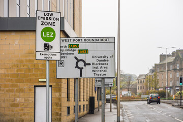 LEZ Low Emission Zone Sign on Metal Post Beside Road for Dundee City Clean Air Initiative with Blurred Cars Approaching Roundabout
