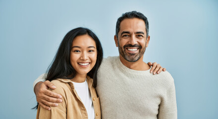 Fototapeta premium Smiling young asian female and mature hispanic male against blue background