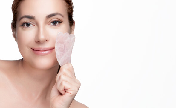 Woman using a rose quartz gua sha for facial massage