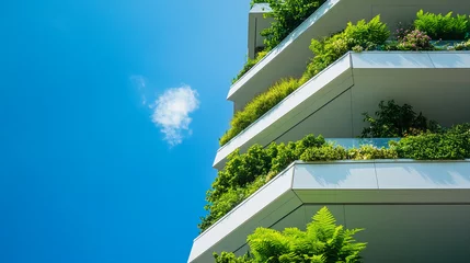 Poster Modern building facade with lush greenery on balconies, showcasing sustainable architecture against a bright blue sky, representing eco-friendly design and urban nature integration